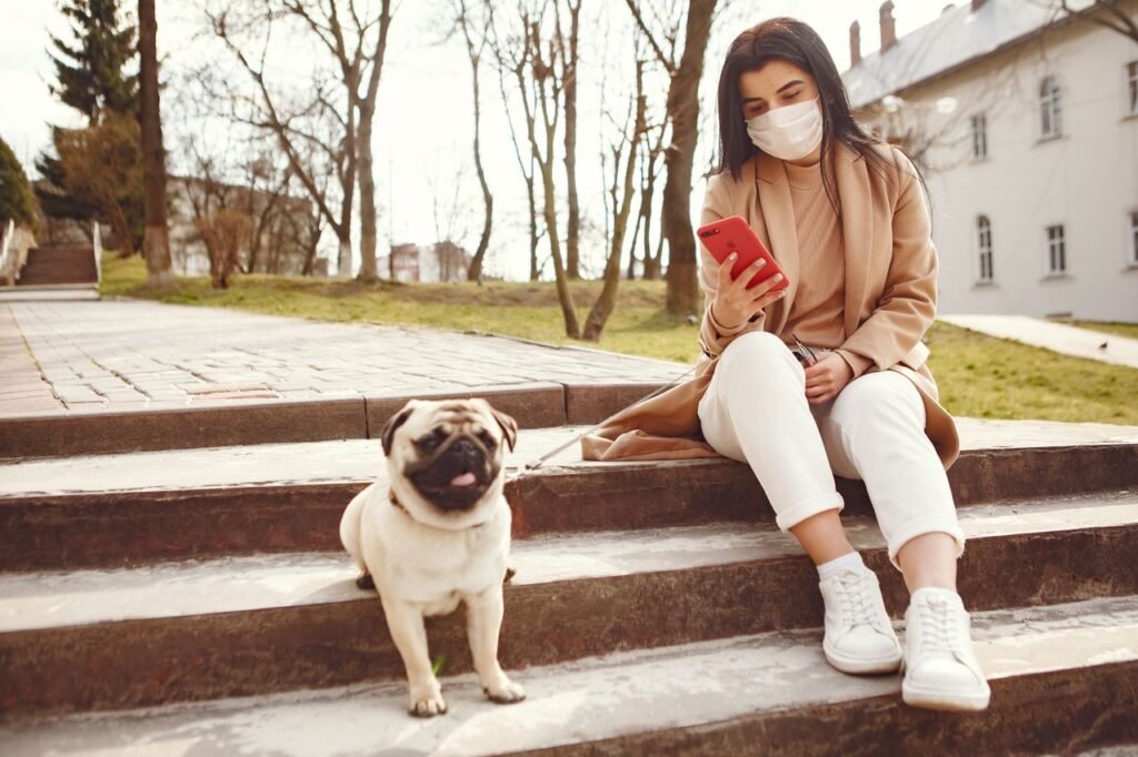 pexels photo 4148817 Full body dark haired female in medical mask in casual wear browsing smartphone on stairs near pavement while walking pug in square trackedtails